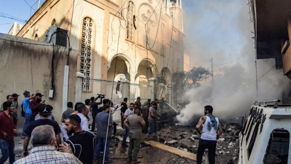 People extinguish a fire at the scene of a car bomb explosion outside the Syriac Orthodox Church of the Virgin Mary in the predominantly Christian neighbourhood of al-Wasti in the Kurdish-majority city of Qamishli in northeast Syria on July 11, 2019. (AFP)