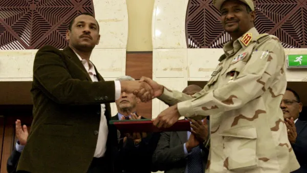 Sudanese deputy chief of the ruling miliary council Mohamed Hamdan Dagalo (R) and protest movement Alliance for Freedom and Changes leader Ahmad al-Rabiah shake hands after inking an agreement before African Union and Ethiopian mediators in Khartoum early on July 17, 2019. (AFP/ File Photo)