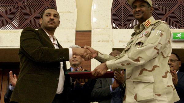 Sudanese deputy chief of the ruling miliary council Mohamed Hamdan Dagalo (R) and protest movement Alliance for Freedom and Changes leader Ahmad al-Rabiah shake hands after inking an agreement before African Union and Ethiopian mediators in Khartoum early on July 17, 2019. (AFP)