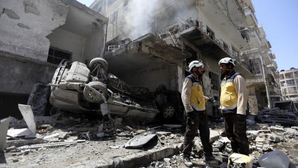 Members of the Syrian Civil Defence (White Helmets) gather at the site of a reported air strike on the town of Ariha, in the south of Syria's Idlib province on July 28, 2019. (Omar HAJ KADOUR / AFP)