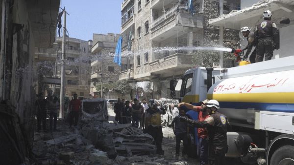 Members of the Syrian Civil Defence (White Helmets) extinguish a fire at the site of a reported air strike on the town of Ariha, in the south of Syria's Idlib province on July 28, 2019. (Omar HAJ KADOUR / AFP)