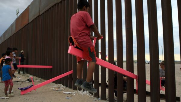 American and Mexican families play with a toy called "up and down" (seesaw swing) over the Mexican border with US at the Anapra zone in Ciudad Juarez, Chihuahua State, Mexico. (AFP/ File Photo)