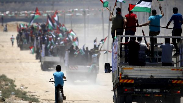 Palestinian demonstrators wave their national flag as they drive towards the border fence with Israel, east of Gaza City on July 22, 2019. (MOHAMMED ABED / AFP)