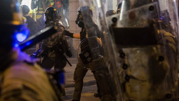 Riot police walk amid tear gas fired at protesters in an attempt to disperse them in Hong Kong (AFP)