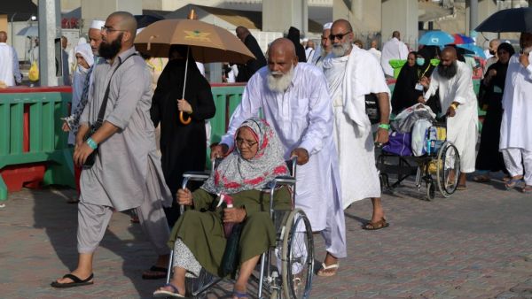 A Muslim worshipper seated in a wheelchair is pushed as she and her escort arrive in Mina to throw pebbles as part of the symbolic al-A'qabah. (AFP)