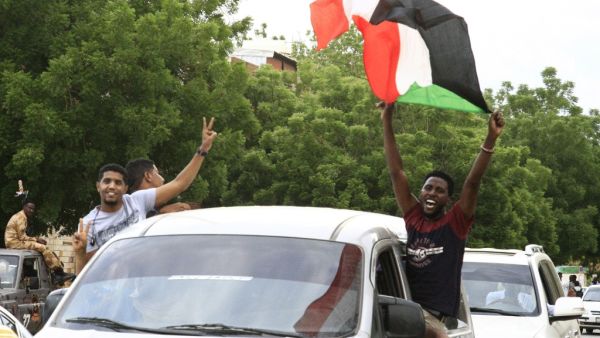 A Sudanese man waves a national flag as people celebrate outside the Friendship Hall in the capital Khartoum where generals and protest leaders signed a historic transitional constitution meant to pave the way for civilian rule in Sudan, on August 17, 2019. (AFP/ File Photo)
