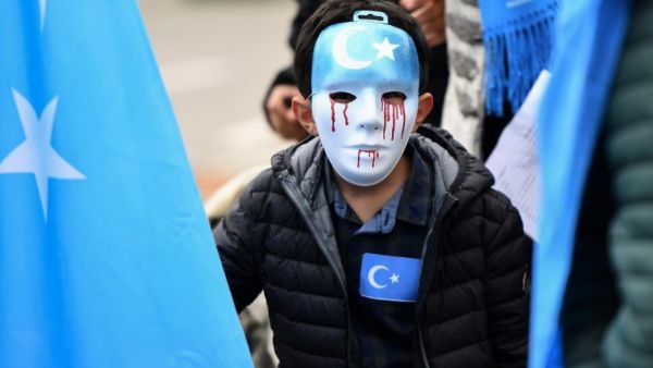 Boy wears mask with tears of blood during recent protest of ethnic Uighurs in Brussels asking EU to pressure China to close 're-education centres' (AFP/file photo)