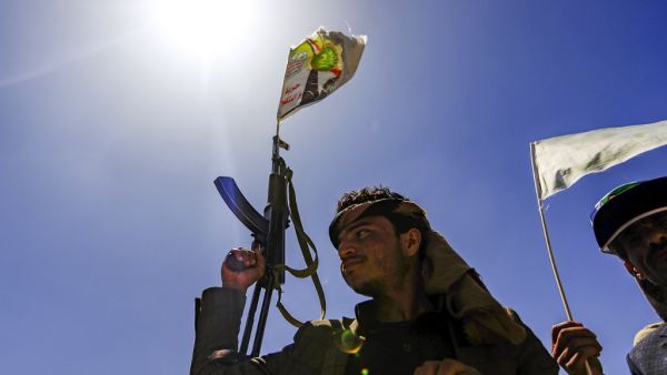 A Yemeni man holds up a Kalashnikov assault rifle with a flag sticking from its barrel showing a picture of the Huthi rebel leader Abdulmalik al-Huthi, during a tribal meeting in the Huthi rebel-held capital Sanaa on September 21, 2019, as tribesmen donate rations and funds to fighters loyal to the Huthis along the fronts. (Mohammed HUWAIS / AFP)