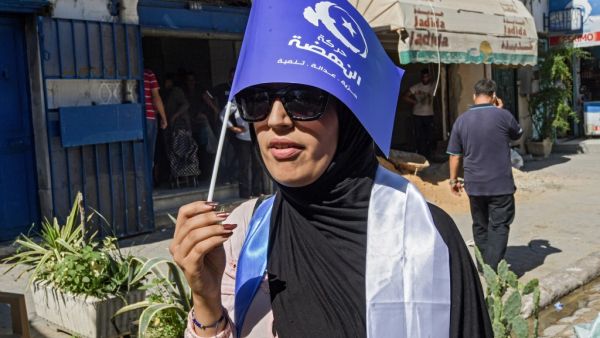 A woman walks holding up a flag of the Islamist-inspired Ennahda party while campaigning in the upcoming upcoming legislative elections in the capital Tunis on October 1, 2019. (FETHI BELAID / AFP)