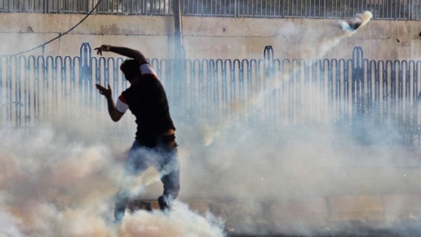 An Iraqi demonstrator gestures amidst smoke from burning tyres and tear gas during a demonstration against state corruption, failing public services and unemployment, in the Iraqi capital Baghdad on October 5, 2019. (AFP/ File Photo)