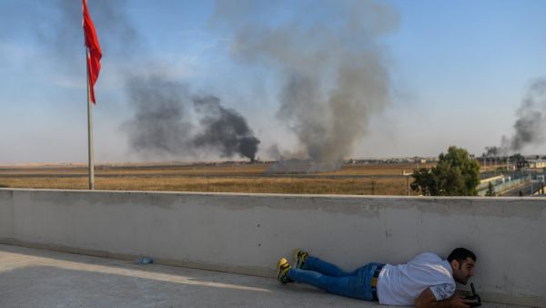 A journalist takes cover in Akcakale near the Turkish border with Syria on October 10, 2019 as a mortar landed nearby, on the second day of Turkey's military operation against Kurdish forces. (AFP)