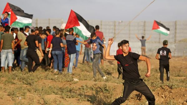 A Palestinian protester uses a slingshot to hurl stones during clashes with Israeli forces following a demonstration by the border fence between the Gaza Strip and Israel, east of Gaza City, on October 11, 2019. (SAID KHATIB / AFP)