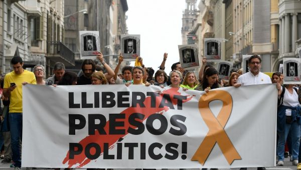 People protest holding a banner reading "Free political prisoners" in Barcelona on October 14, 2019, after Spain's Supreme Court sentenced nine Catalan leaders to prison terms ranging from nine to 13 years for sedition and misuse of public funds for their role in a failed 2017 independence bid. (LLUIS GENE / AFP) People protest holding a banner reading "Free political prisoners" in Barcelona on October 14, 2019, after Spain's Supreme Court sentenced nine Catalan leaders to prison terms ranging from nine to 13 years for sedition and misuse of public funds for their role in a failed 2017 independence bid. (LLUIS GENE / AFP)