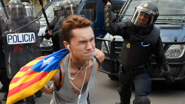 A Spanish national police officer uses his club to hit a protester during a demonstration called the Catalan pro-independence left youth group 'Arran' (AFP)