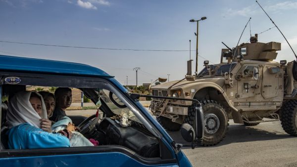 A US military vehicle drives on a road after US forces pulled out of their base in the Northern Syriain town of Tal Tamr on October 20, 2019, as members of a Syrian family fleeing the countryside of Ras al-Ain head north in a van to the region of al-Hasakeh. US forces withdrew from a key base in northern Syria today, a monitor said, two days before the end of a US-brokered truce to stem a Turkish attack on Kurdish forces in the region. Delil SOULEIMAN / AFP