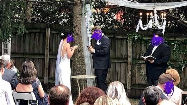 Newlyweds, believed to be from the US, are both typing away on their phones as they stand next to their officiant in a photograph (pictured) shared on social media, last week (Facebook)