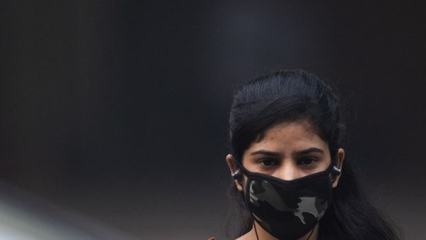 A woman wearing a protective face mask walks along a street in smoggy conditions in New Delhi on November 4, 2019. Millions of people in India's capital started the week on November 4 choking through "eye-burning" smog, with schools closed, cars taken off the road and construction halted. Jewel SAMAD / AFP