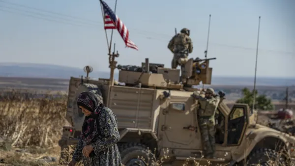 A Syrian elderly woman walks past a US armoured vehicle on patrol in the village of Ein Diwar in Syria's northeastern Hasakeh province on November 4, 2019.  Delil SOULEIMAN / AFP