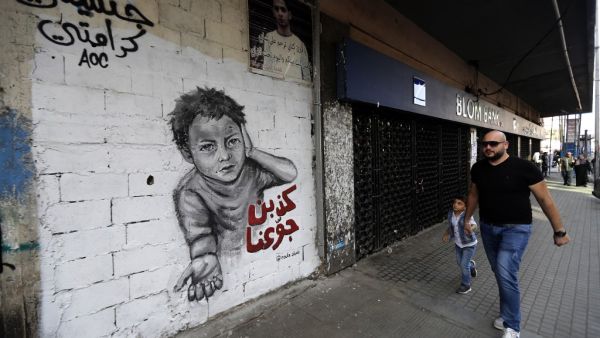 A man walks past a graffiti drawn on the wall of a building at the al-Nour Square in the northern port city of Tripoli  (AFP)