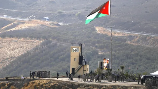 A picture taken from the Israeli side of the border shows King Abdullah II of Jordan (L) standing to attention with army troops under a Jordanian national flag during a ceremony at the Jordan Valley site of Naharayim, also known as Baqura, east of the Jordan River on November 11, 2019. (AFP/ File Photo)