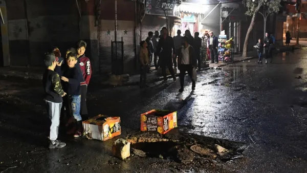 Syrian children stand around a whole on the road following a reported rocket attack in the government-held northern city of Aleppo on November 21, 2019. AFP
