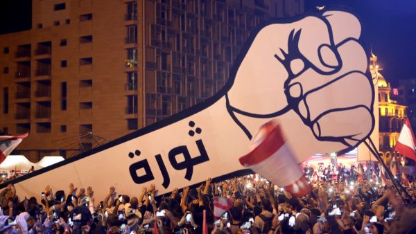 Lebanese demonstrators raise a new giant sign of a fist that bears the Arabic word "revolution" on it, in the Lebanese capital Beirut's Martyr's Square on November 22, 2019, after the sign was burnt overnight by unknown perpetrators. (AFP/ File )