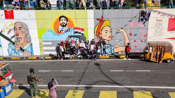 Protesters pose for a picture by graffiti murals during an anti-government demonstration in the Iraqi capital Baghdad's Tahrir Square on November 23, 2019. (SABAH ARAR / AFP)