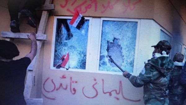 تظهر الصور مسلحين أمام الجدار بعد أن علقوا على نافذته علم "كتائب حزب الله"