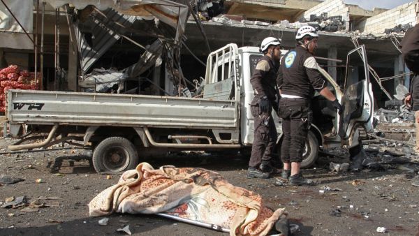 The body of a victim lies on the ground near members of the Syrian Civil Defence (White Helmets) following a regime air strike on December 2, 2019 in a market in the town of Maaret al-Numan in the jihadist-run Syrian province of Idlib. Regime air strikes killed 10 civilians and wounded at least 15 in Syria's last major opposition bastion, where deadly clashes between regime forces and armed groups have escalated in the past two days, the Britain-based Syrian Observatory for Human Rights added said. Abdulazi