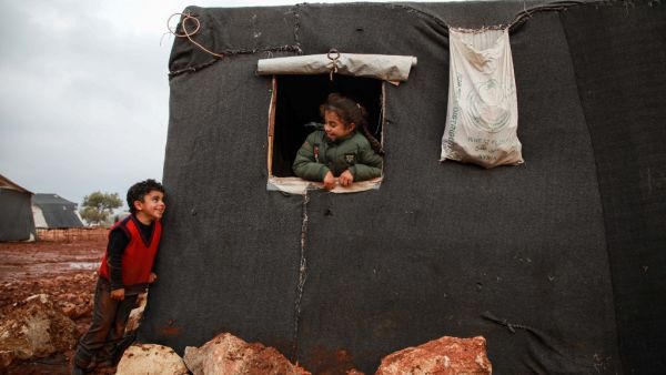 A boy and a girl looking out the window of a tent exchange glances, at a flooded camp for displaced Syrians near the village of Killi in the north of the northwestern Idlib province on December 5, 2019. Aaref WATAD / AFP