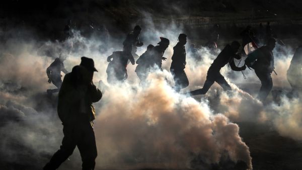 Palestinian protesters run from tear gas fired by Israeli forces amid clashes during a demonstration along the border with Israel east of Bureij in the central Gaza Strip on December 6, 2019. MAHMUD HAMS / AFP