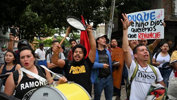 People demonstrate demanding the resignation of Colombian President Ivan Duque, upon his arrival at the community hall of the Aguablanca neighborhood, in Cali, Colombia, on December 6, 2019, to attend a national dialogue convened in response to protests against his government. Luis ROBAYO / AFP