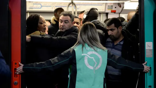 A Paris public transports operator RATP employee stands as commuters board on a RER B regional train at Chatelet-les Halles station in Paris on December 9, 2019 during a strike of RATP employees over French government's plan to overhaul the country's retirement system, as part of a national strike. (Aurore MESENGE / AFP)