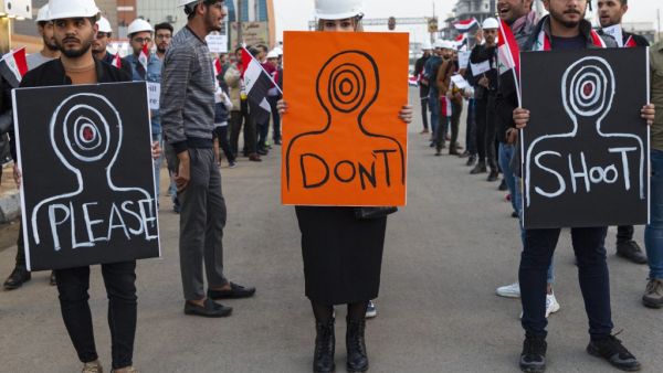 Iraqi protesters wearing protective helmets carry placards during a rally near the local government headquarters in the southern city of Basra on December 13, 2019, as they take part in ongoing anti-government demonstrations. (AFP/ File Photo)