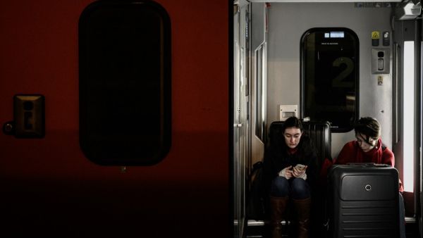 Travellers waiting for departure sit between two coaches at the Gare de Lyon railway station in Paris on December 20, 2019, on the 16th day of a nationwide multi-sector strike against the government's pensions overhaul. Philippe LOPEZ / AFP
