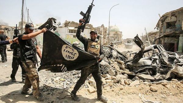 Members of the Iraqi Counter-Terrorism Service cheer in Mosul as they carry upside-down Islamic State flag, with the destroyed Al-Nuri mosque seen in the background on July 2, 2017 (AFP)