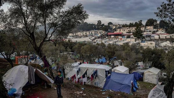 A young boy stands outside a tent at a makeshift camp next to the overcrowded refugee camp of Moria, on the island of Lesbos (AFP)