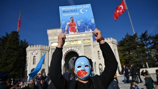 Uighur protesters in Istanbul hold pictures of Mesut Ozil (AFP)