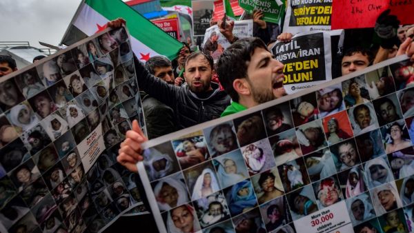 Protesters chant slogans and hold placards reading "More than 30.000 children killed by Russia and Assad regime" and bearing photographs of the victims during a protest against Syrian military operation in the rebel bastion of Idlib, northwestern Syria, taking place near the Russian Consulate, in Istanbul, on December 28, 2019. (AFP/ File Photo)