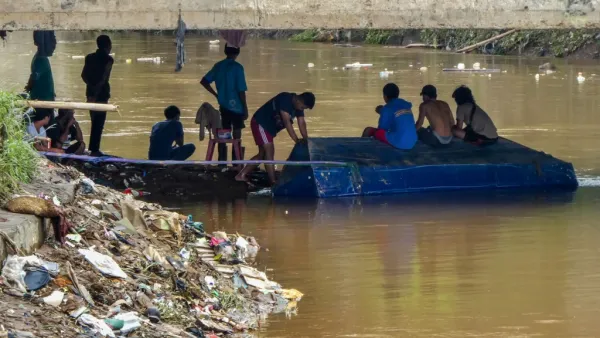 Young men wait under a concrete bridge looking to salvage valuable items carried by the currents in Jakarta on January 3, 2020, after flooding triggered by heavy rain which started on New Year's Eve hit the area. (AFP/ File Photo)