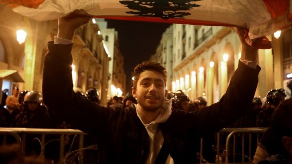 A Lebanese protester waves a national flag during an anti-government demonstration near the parliament in Beirut's downtown district on January 16, 2019. Lebanon's security forces released most of the 100 plus anti-government protesters detained in the past 48 hours, lawyers told AFP, after two nights of violent demonstrations in Beirut. PATRICK BAZ / AFP