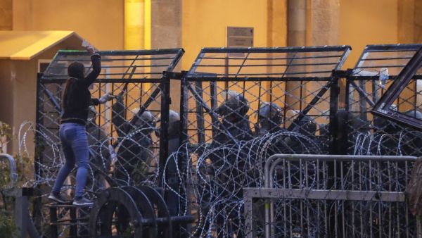 Anti-government protesters attempt to break through the security barrier in the central downtown district of the Lebanese capital Beirut near the parliament headquarters during clashes with security forces on January 18, 2020. ANWAR AMRO / AFP
