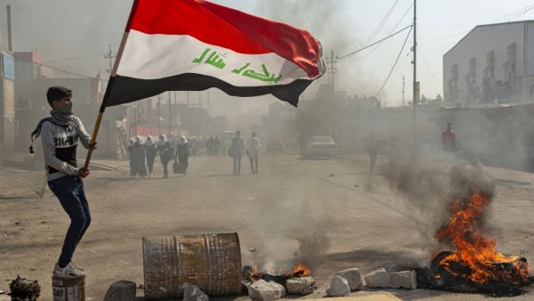 An anti-government protester waves an Iraqi national flag at a make-shift roadblock during clashes with security forces in Iraq's southern city of Basra on January 20, 2020. Hussein FALEH / AFP