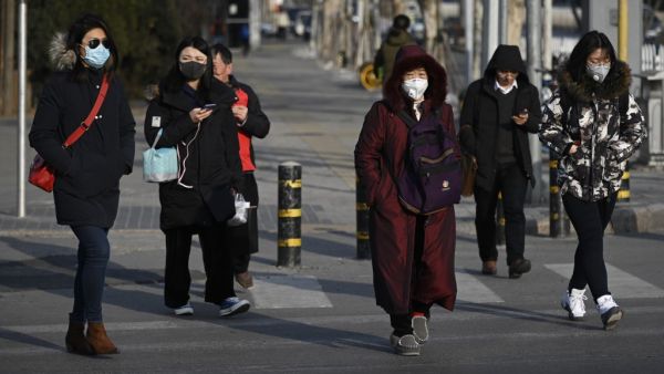 Pedestrians wearing masks cross a street in Beijing on January 21, 2020. The number of people in China infected by a new SARS-like virus jumped to 291 on January 21, according to authorities.  WANG Zhao / AFP