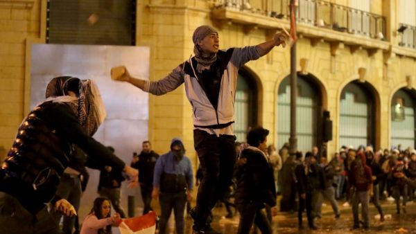 A Lebanese anti-government protester hurls stones at riot police during clashes in downtown Beirut on January 22, 2020. Lebanon's new prime minister claims to lead a government of technocrats but critics, including protesters, argue the line-up is window dressing for a set of ministers who are neither experts nor independent. PATRICK BAZ / AFP