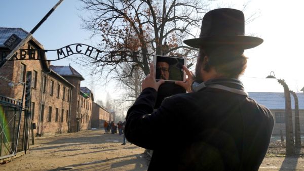  In this file photo taken on December 05, 2019 the face of a visitor is reflected on the screen of his phone as he takes a picture of the main entrance at the Auschwitz German Nazi death camp ahead of German Chancellor Angela Merkel's landmark visit in Oswiecim, Poland. (AFP/ File Photo)