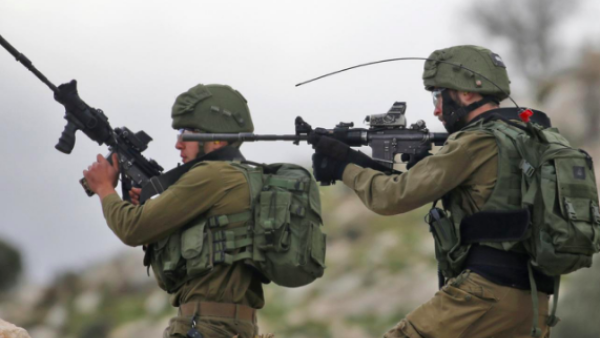 Israeli soldiers hold up their rifles towards Palestinian protesters in the village of Kfar Qaddum, near Nablus in the occupied West Bank (AFP)