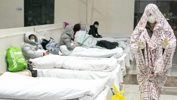 This photo taken on February 5, 2020 shows a patient (R) covered with a bed sheet at an exhibition centre converted into a hospital as it starts to accept patients displaying mild symptoms of the novel coronavirus in Wuhan in China's central Hubei province. China scrambled to find bed space for thousands of newly infected patients on February 6, as the toll from a deadly new virus jumped again with more than 28,000 people known infected nationwide and 563 deaths. STR / AFP