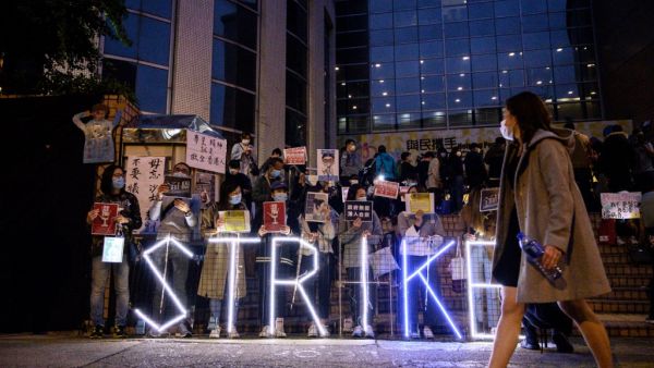 A light installation reading "strike" stands before striking members of the Hospital Authority Employees Alliance (HAEA) and other activists at the Hospital Authority building in Hong Kong on February 7, 2020. AFP
