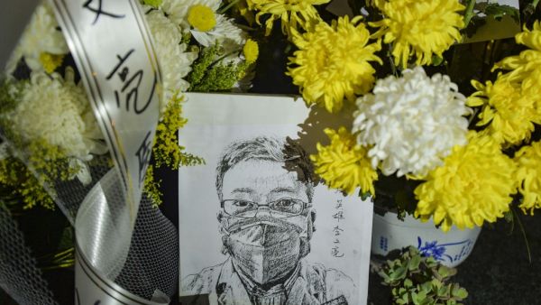 This photo taken on February 7, 2020 shows a photo of the late ophthalmologist Li Wenliang with flower bouquets at the Houhu Branch of Wuhan Central Hospital in Wuhan in China's central Hubei province. AFP